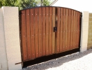 simple arched RV gate with rustic cedar composite and dark brown iron